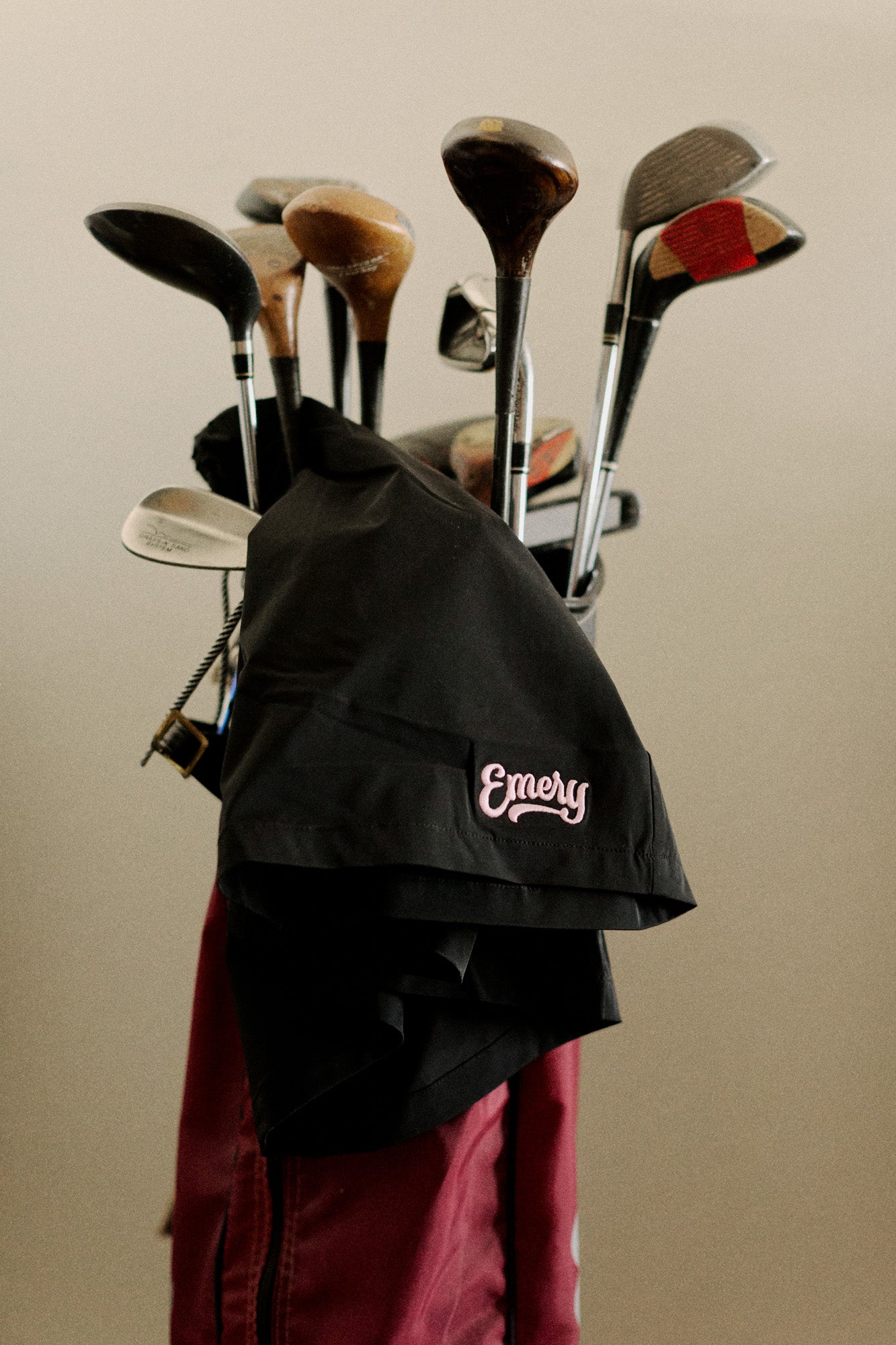 Set of golf clubs in a black bag with 'Emery' branding on a beige background