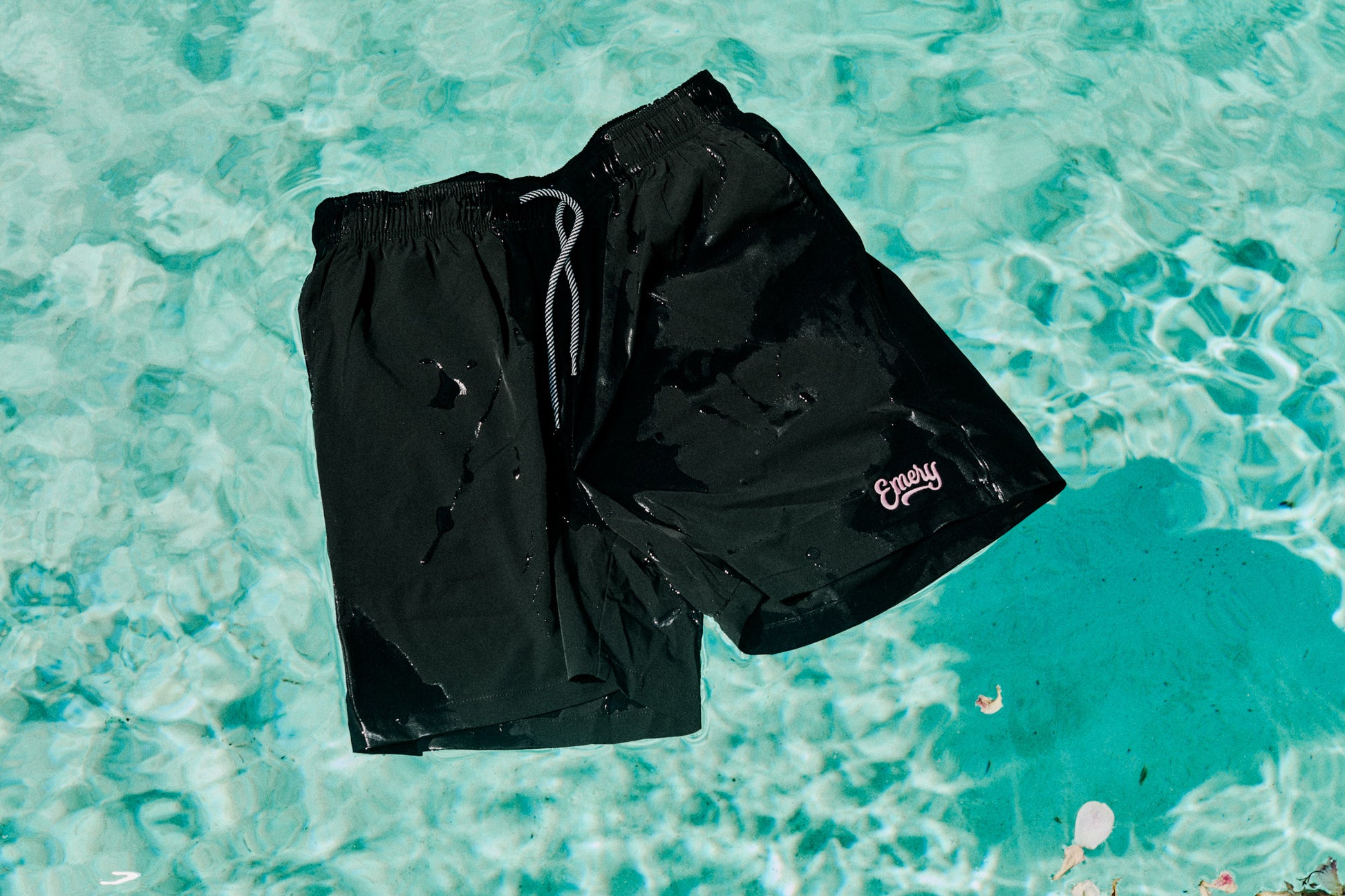 Black shorts with a brand logo on a turquoise water background